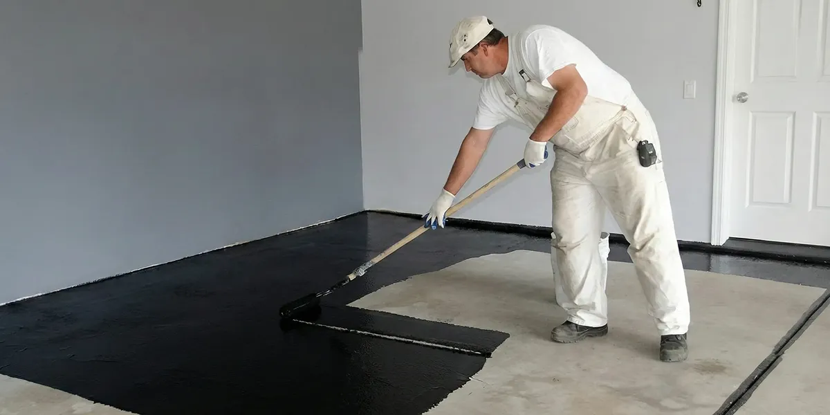 basement waterproofing professional applying waterproof coating to protect a basement floor in Minneapolis, MN